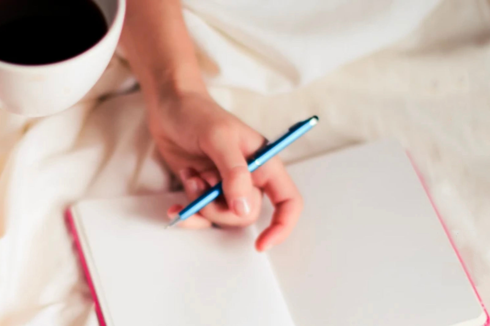 Monday rituals to get your week started right. Image of hand holding a cup of coffee, pen and notebook.