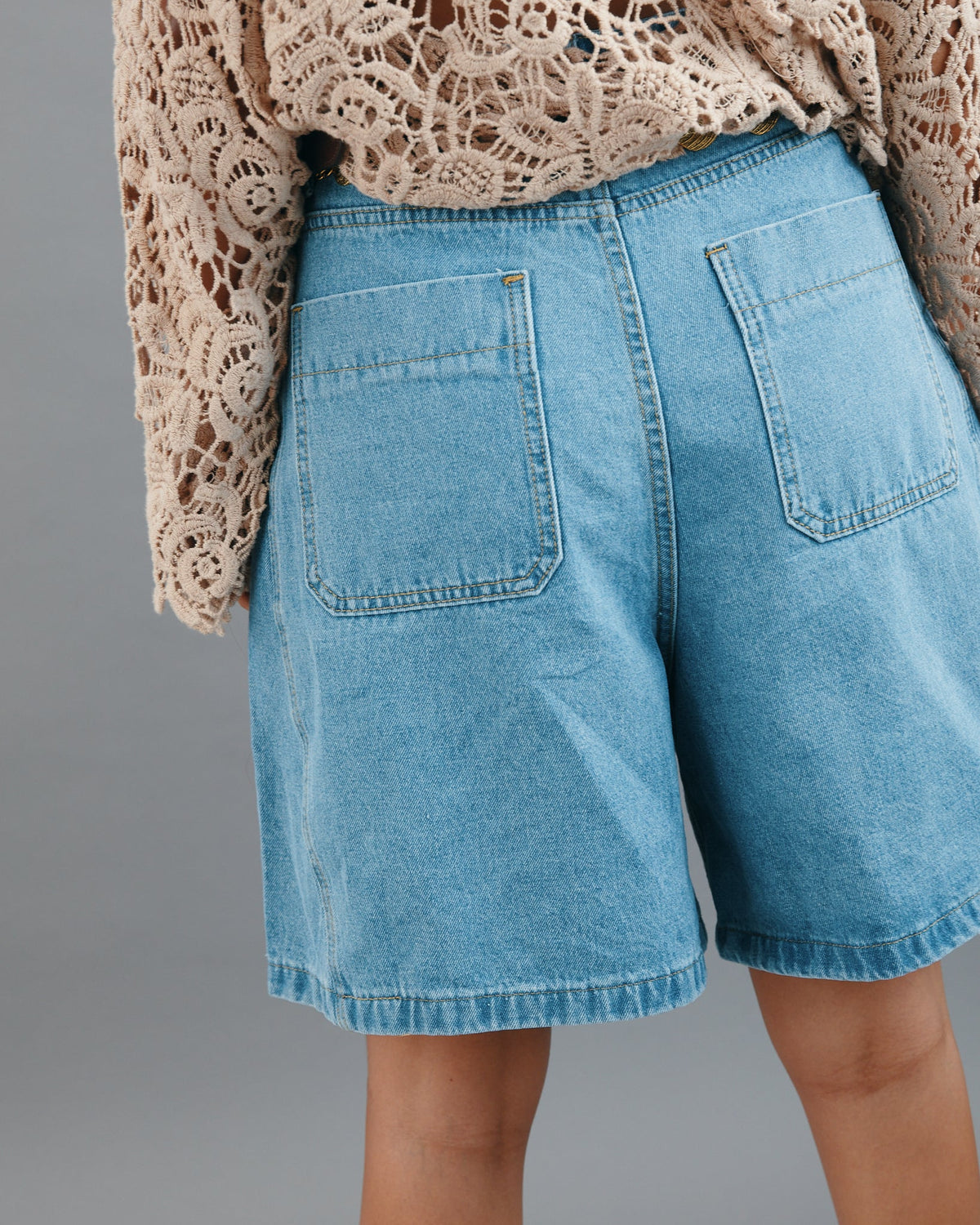 Person wearing blue denim shorts with a neutral background