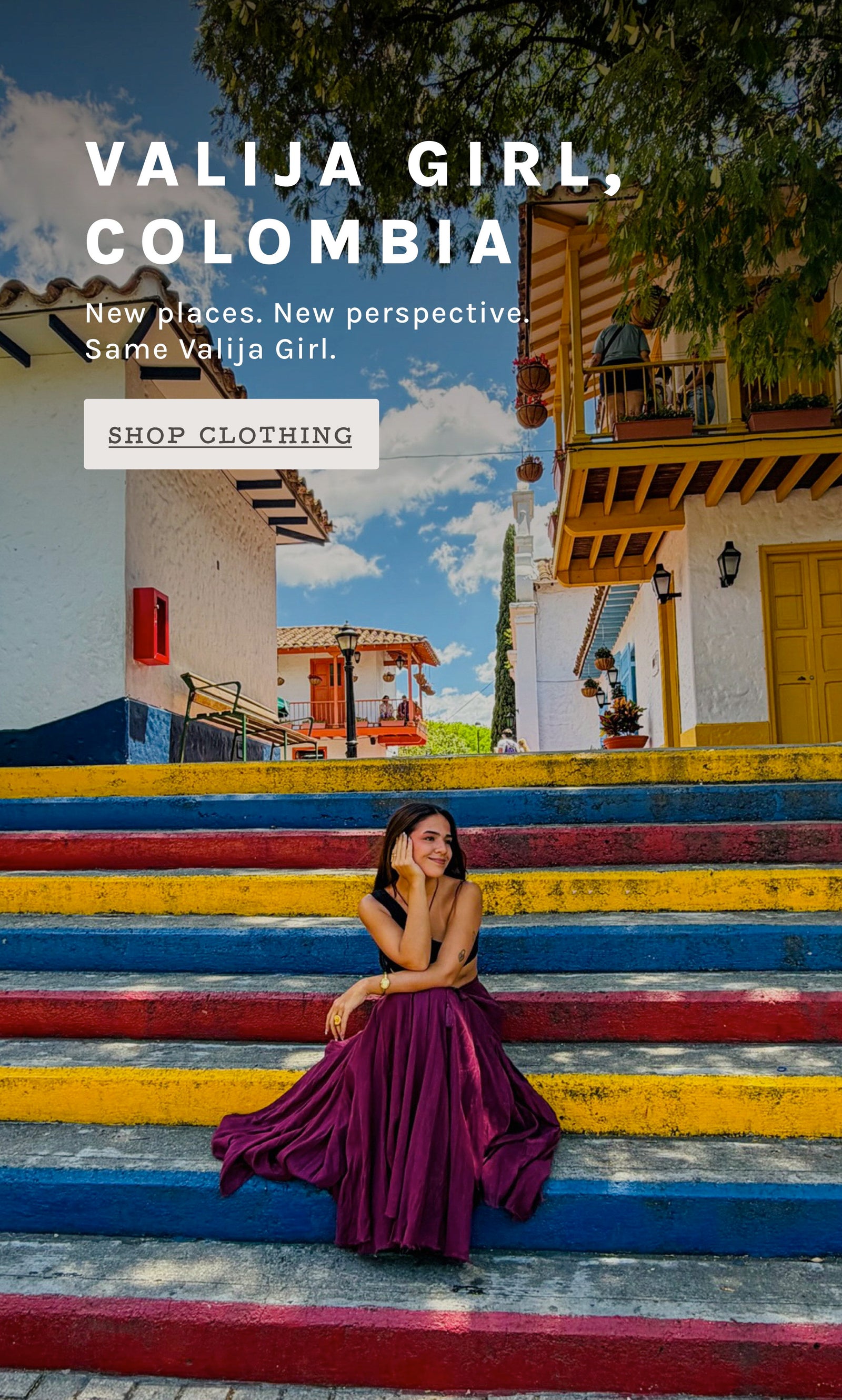 A woman in a flowing deep wine skirt sits on colorful painted steps in front of a colonial-style building. Large overlaid text reads 'VALIJA GIRL, COLOMBIA' with a 'SHOP CLOTHING' button.