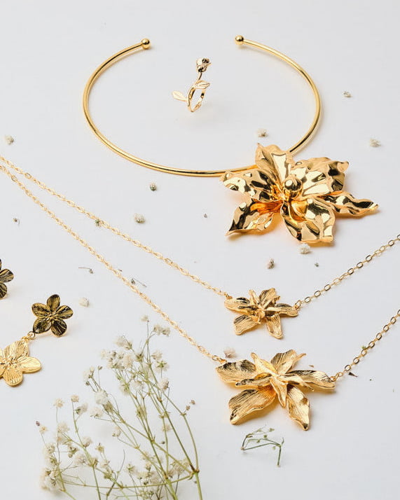 Gold jewelry set with floral designs on a light background