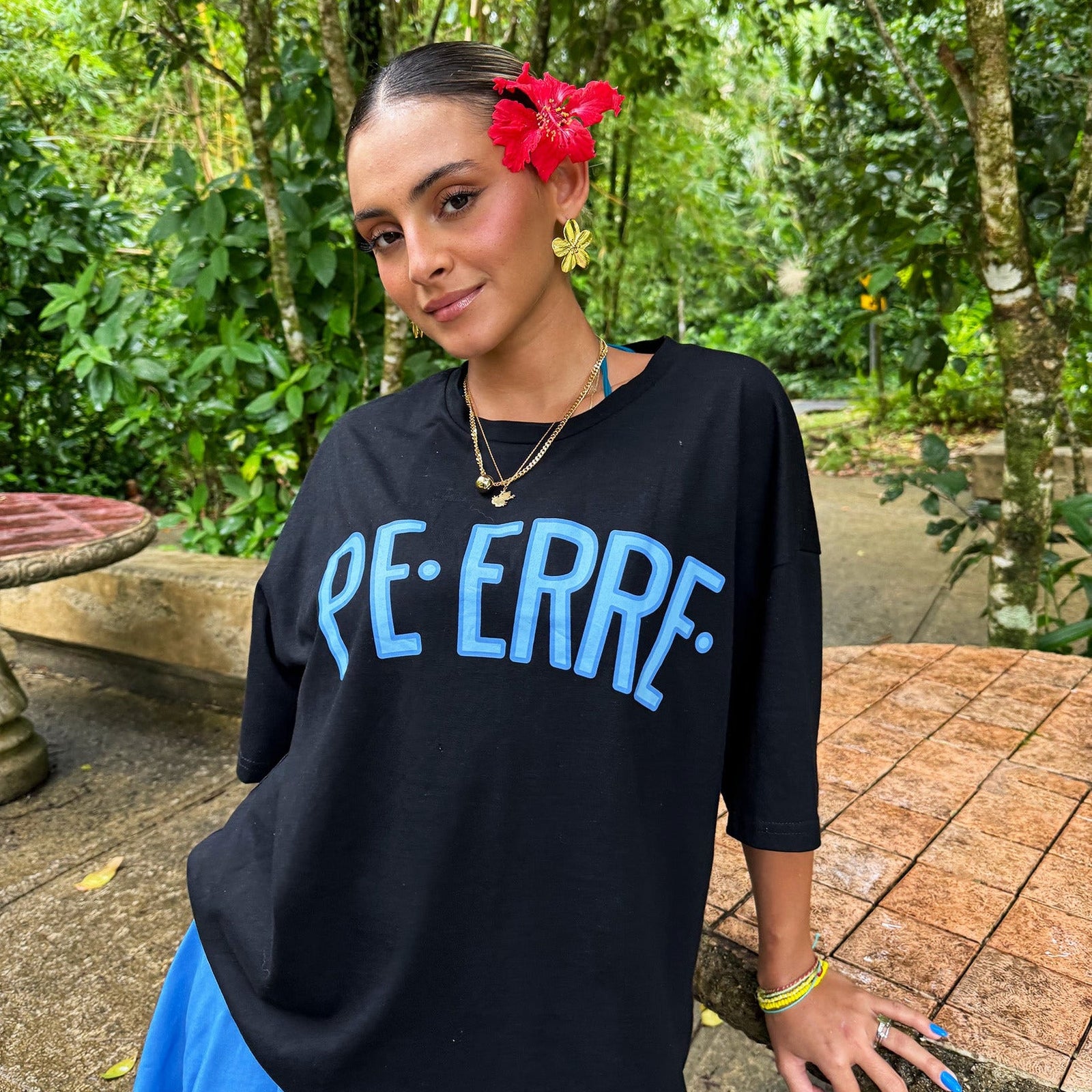 Woman wearing a black sweater with 'PE-ERRE' text in a garden setting